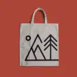 Canvas tote bag with mountain and tree design.