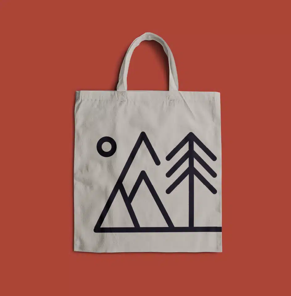 Canvas tote bag with mountain and tree design.