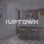 Modern kitchen with bar stools and lighting.